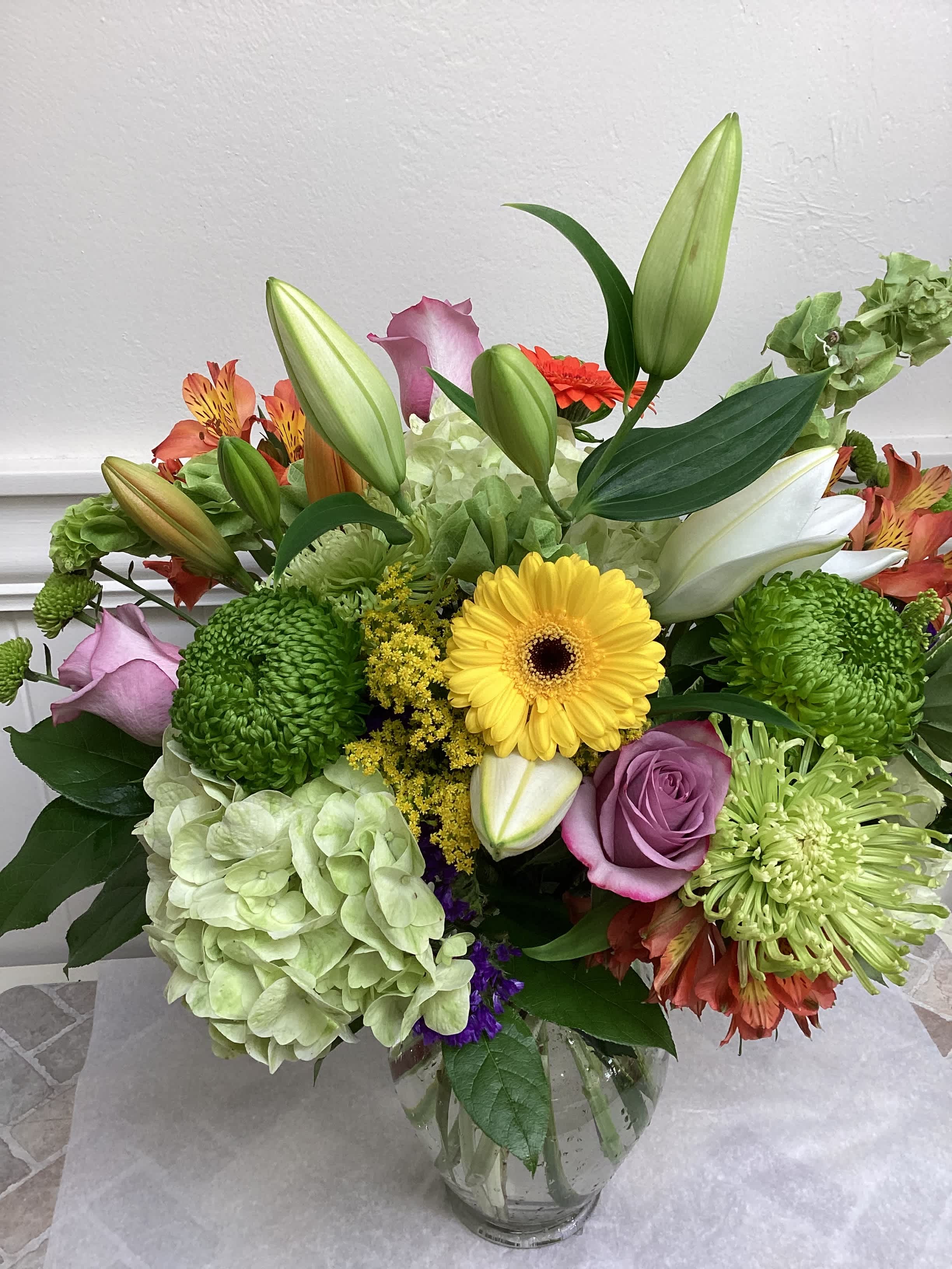 Mixed bouquet in a glass vase with lilies, roses, hydrangea, and chrysanthemums