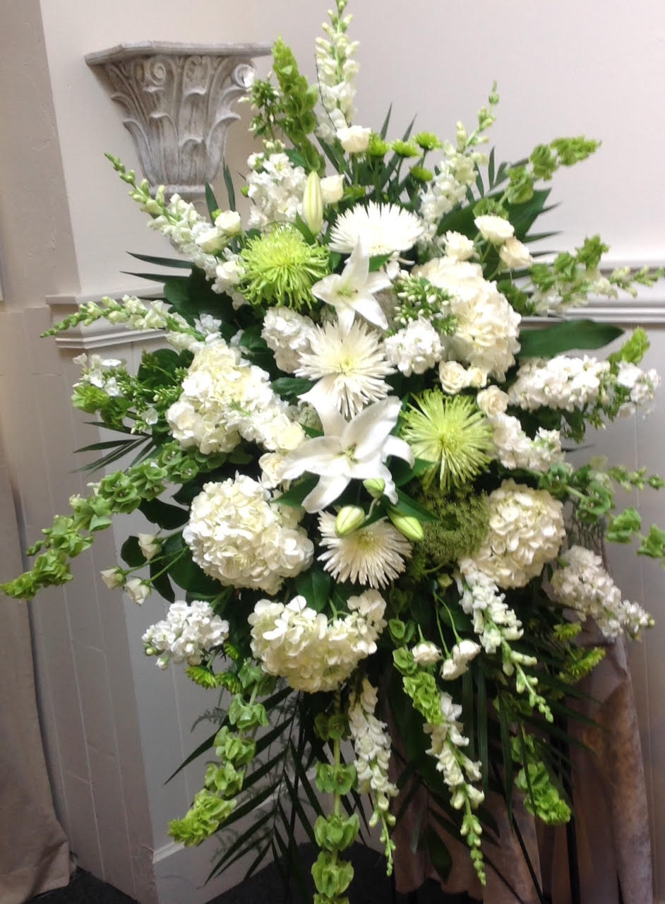 White funeral spray with lilies, hydrangeas, and green accents