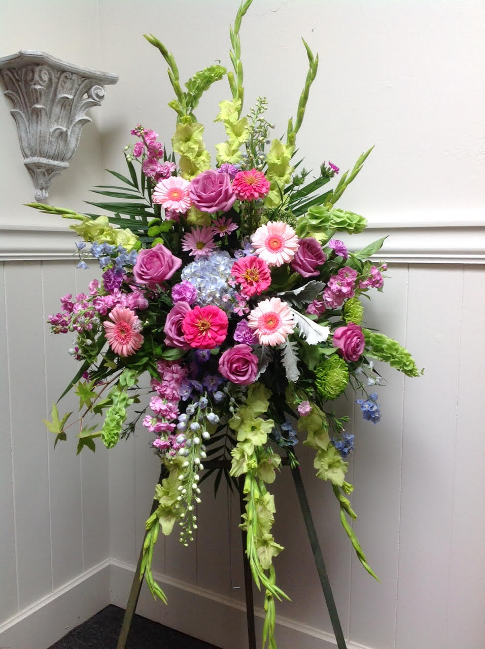Tall floral spray with pink and purple blooms on an easel