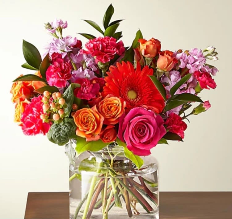 Bright mixed bouquet in a clear glass vase with roses and gerbera daisies