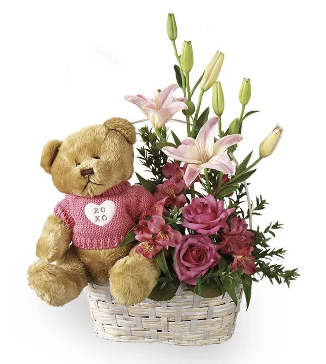 Teddy bear in a basket with pink flowers and lilies