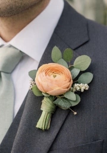 Peach boutonniere with eucalyptus on a suit lapel