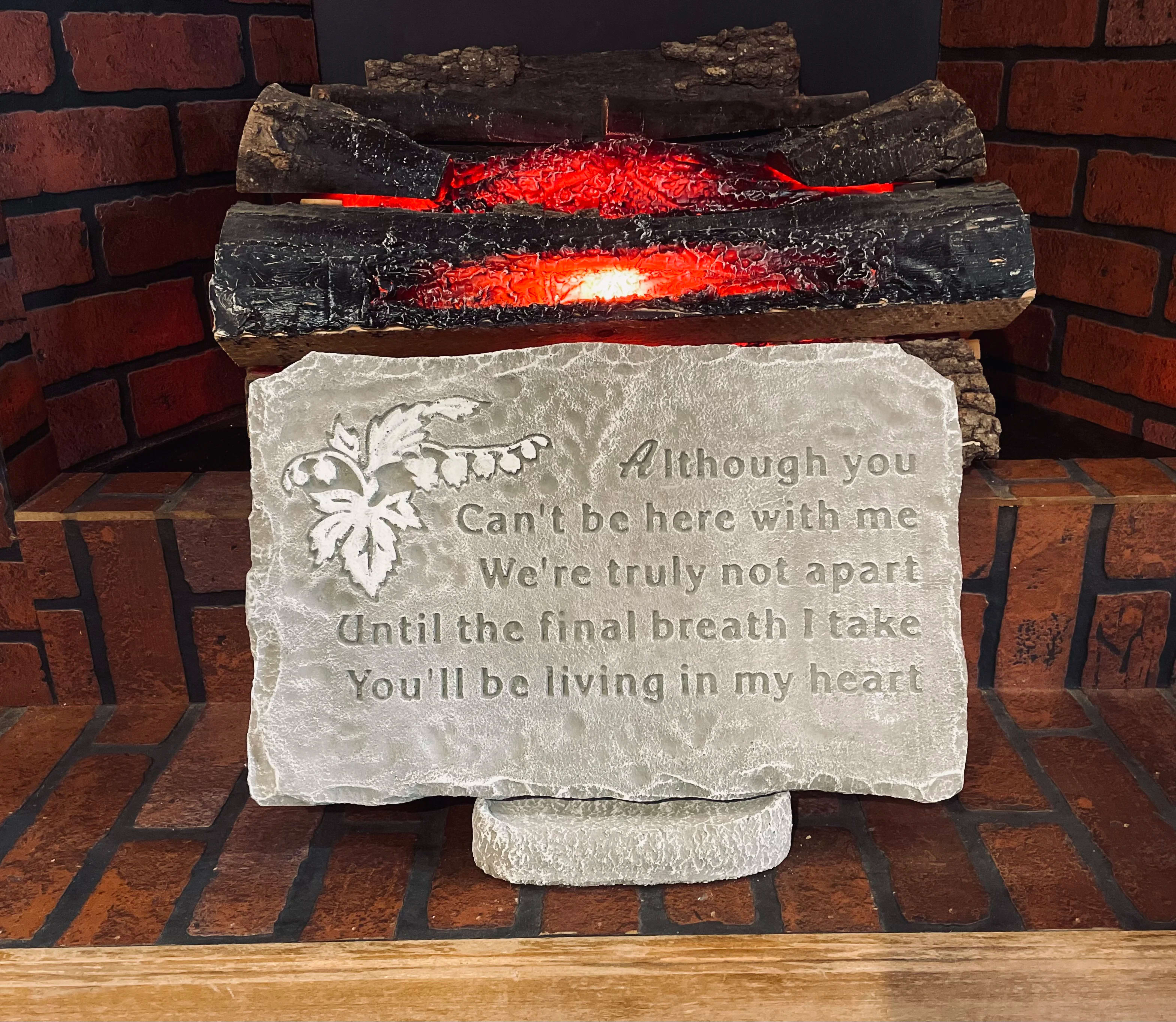 Decorative memorial plaque with an engraved poem in front of faux glowing logs