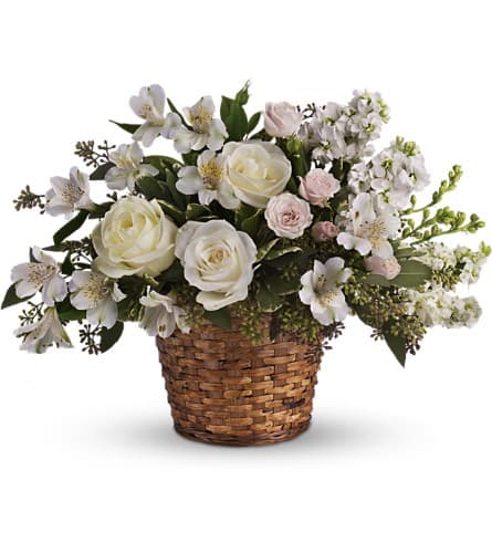 White roses and small white blooms arranged in a wicker basket