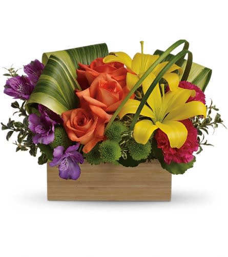 Colorful bouquet of roses, lilies, and purple flowers in a wooden box