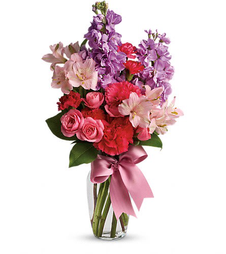 Pink and purple mixed flower bouquet in a glass vase with a ribbon