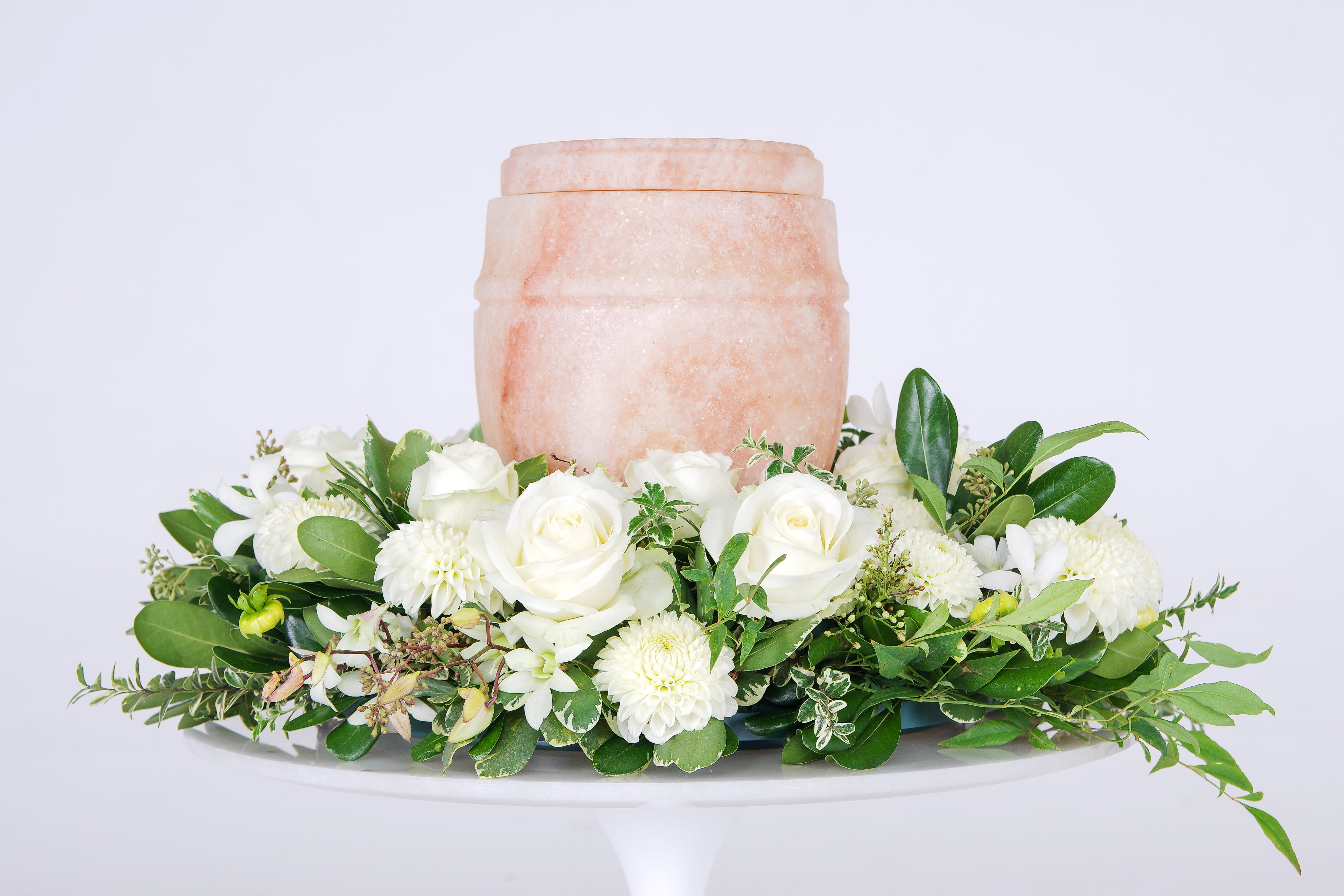 White rose and chrysanthemum arrangement around a peach urn