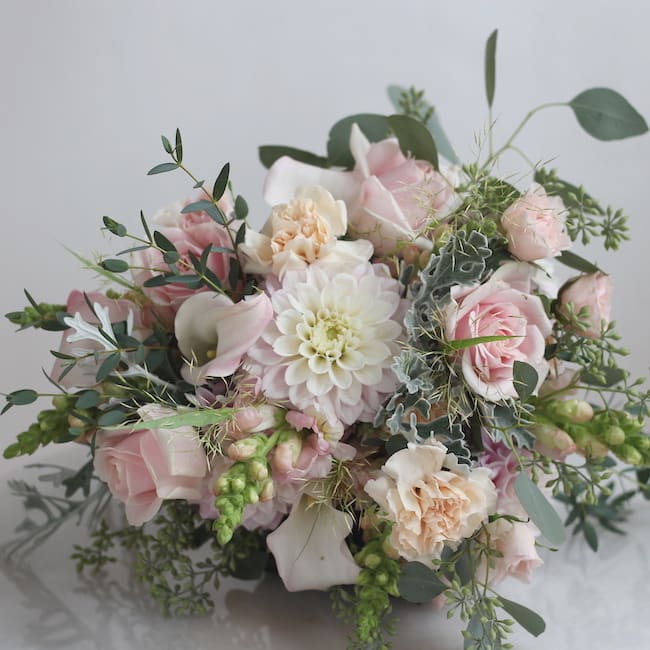 Soft pink and white bouquet with roses, calla lilies, and a central dahlia