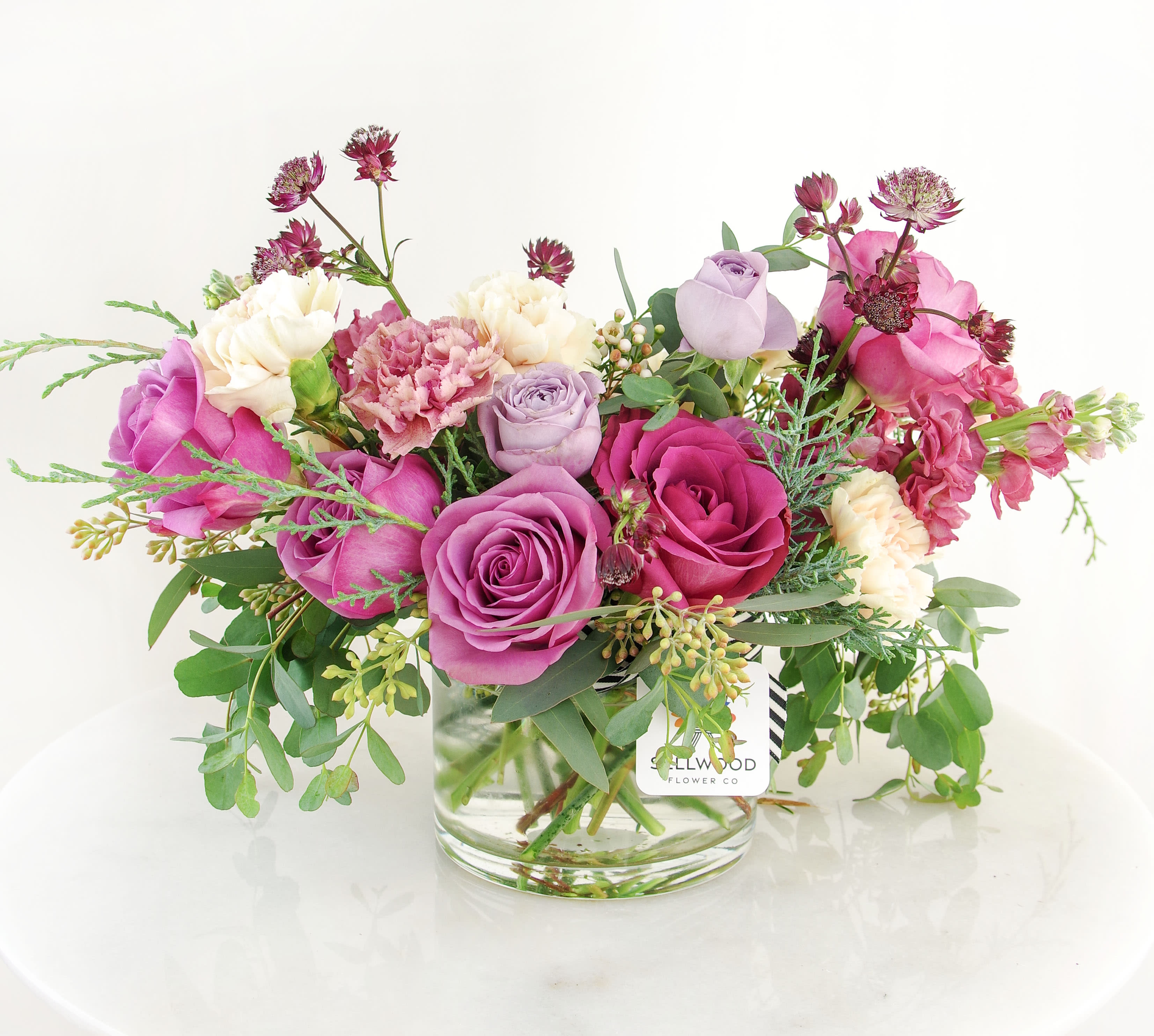 Pink and lavender roses with carnations in a glass vase