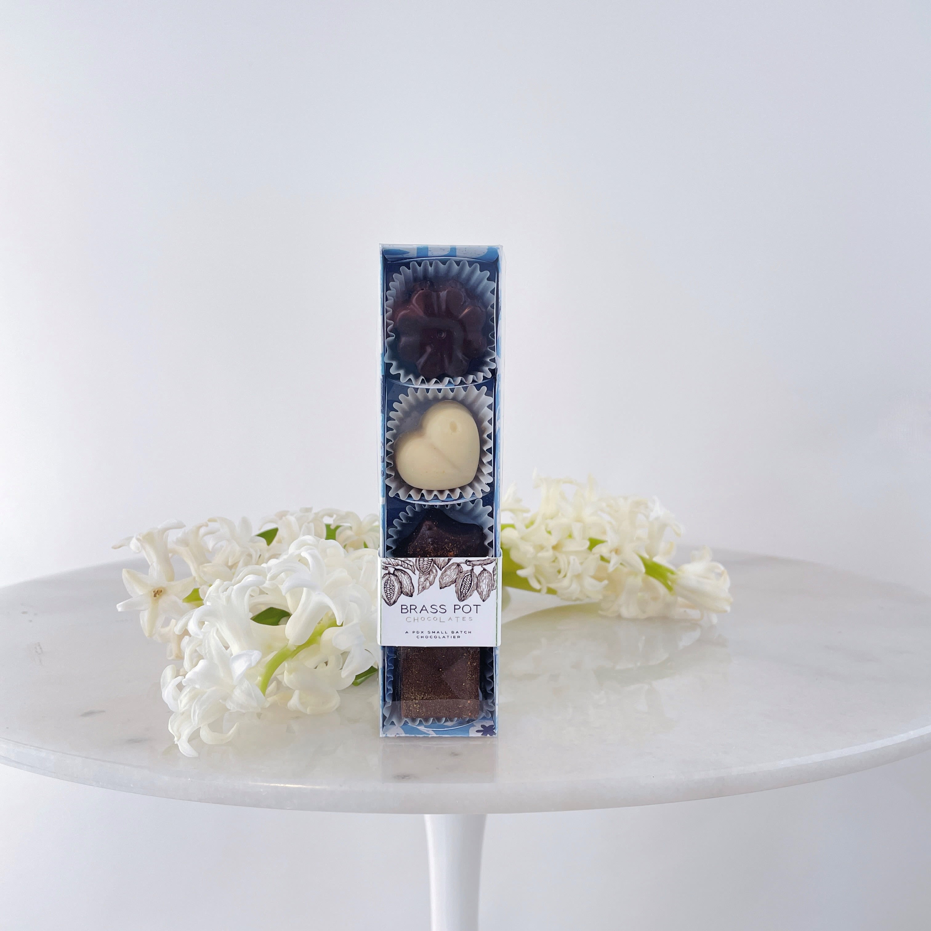 Box of chocolates with white flowers on a table