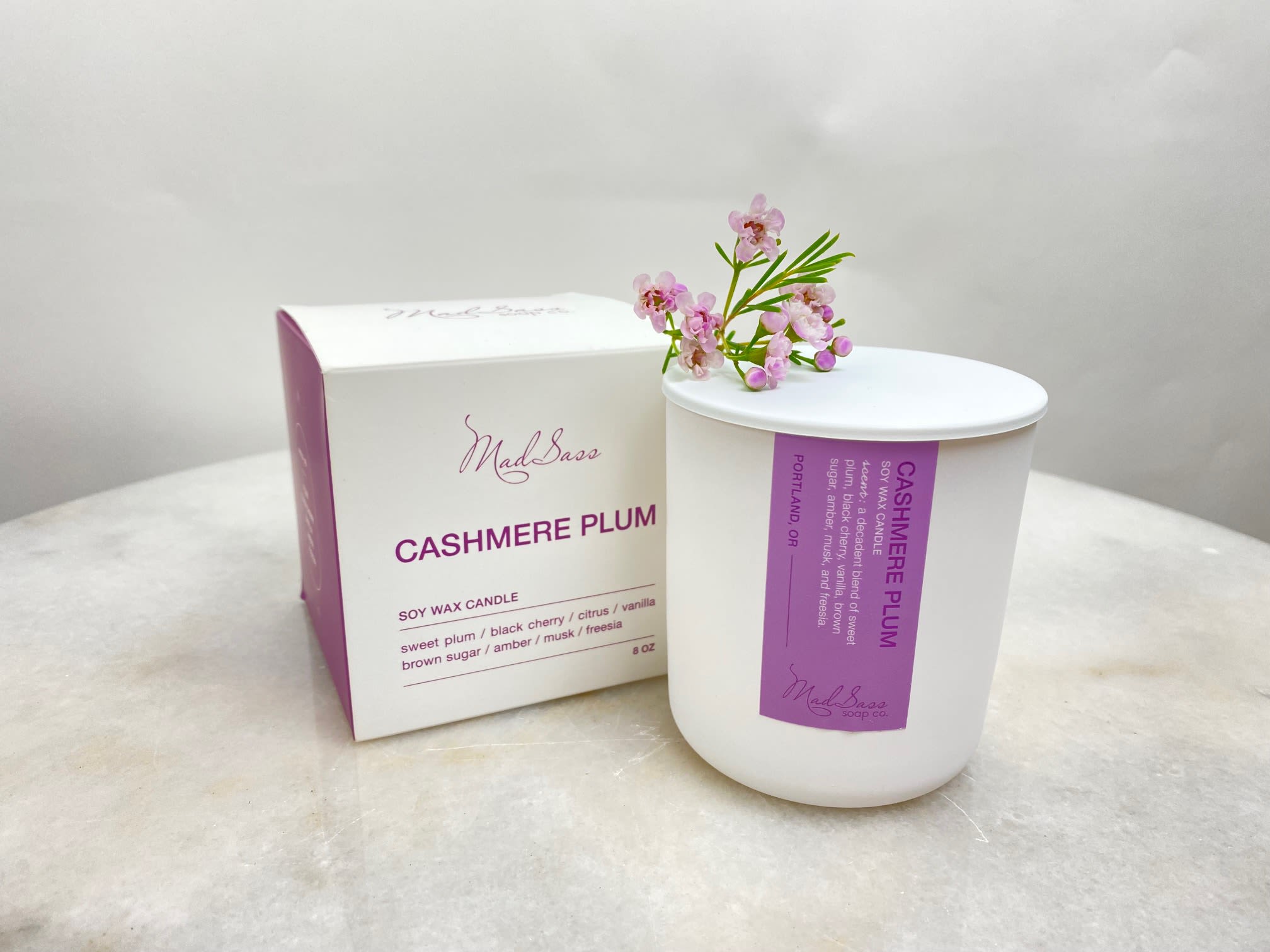White candle in a box with small pink flowers on top