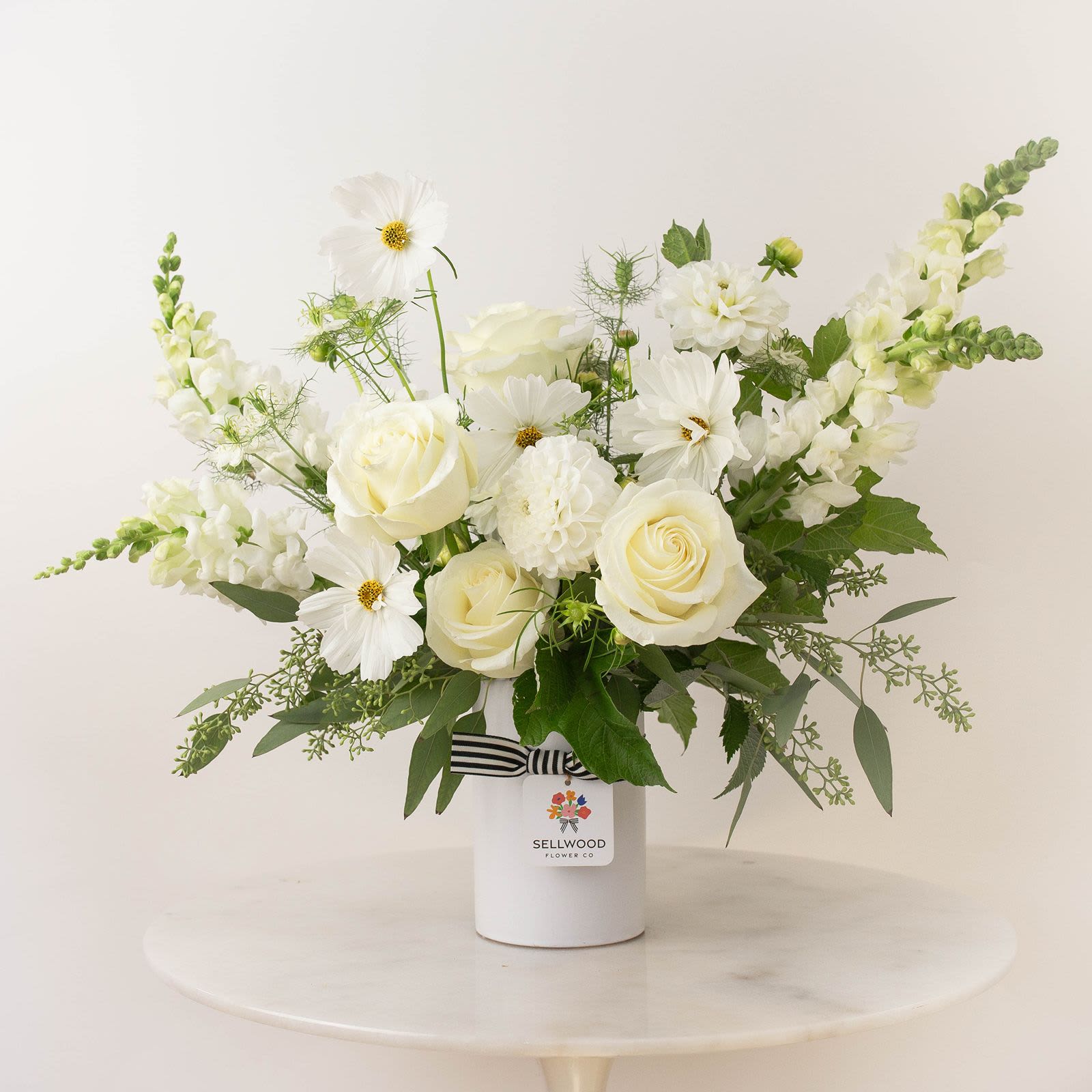 The Quiet Grace - Sympathy - A stunning white bouquet that evokes simplicity, calmness, and peace. This arrangement features a selection of beautiful  flowers.