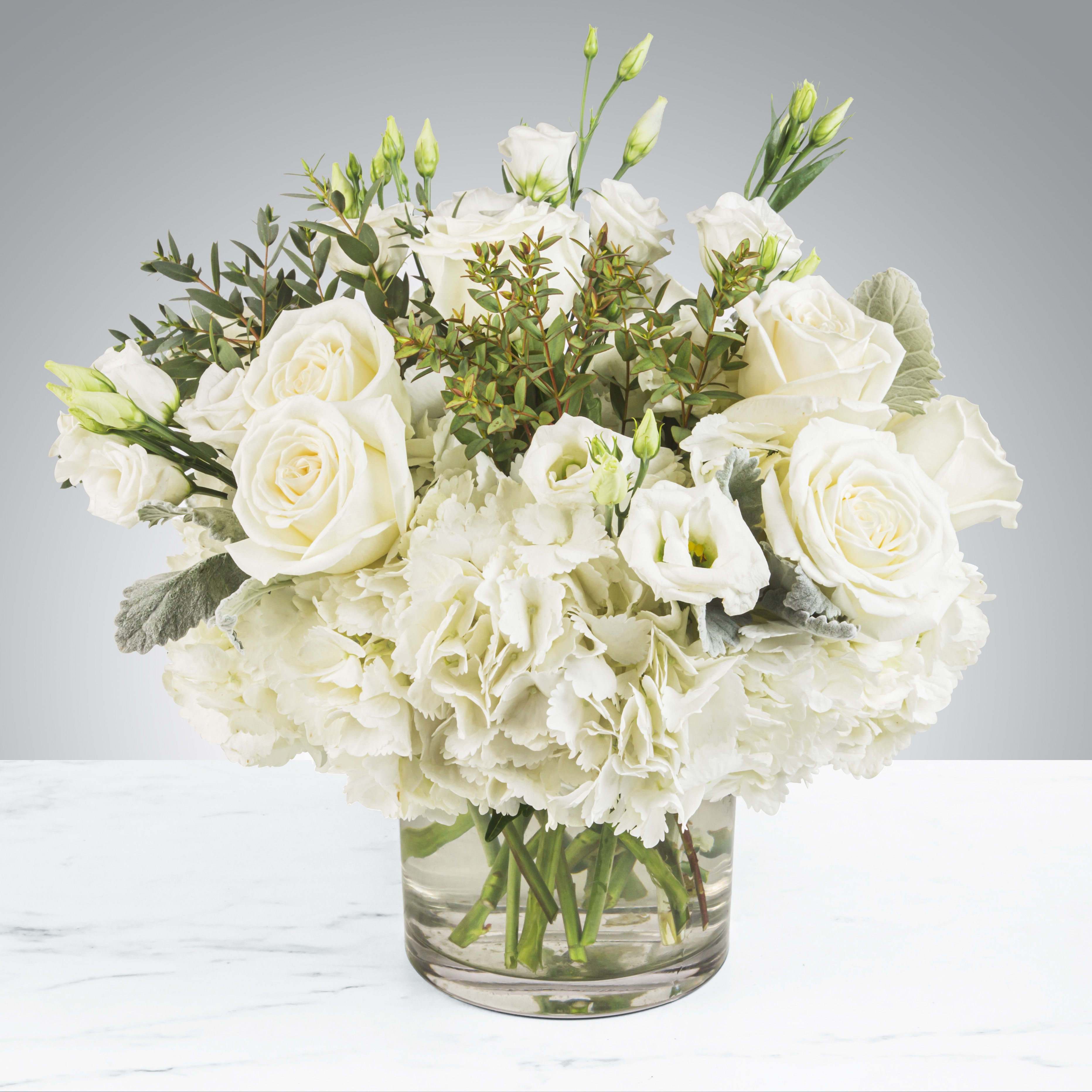 White roses and hydrangeas in a clear glass vase