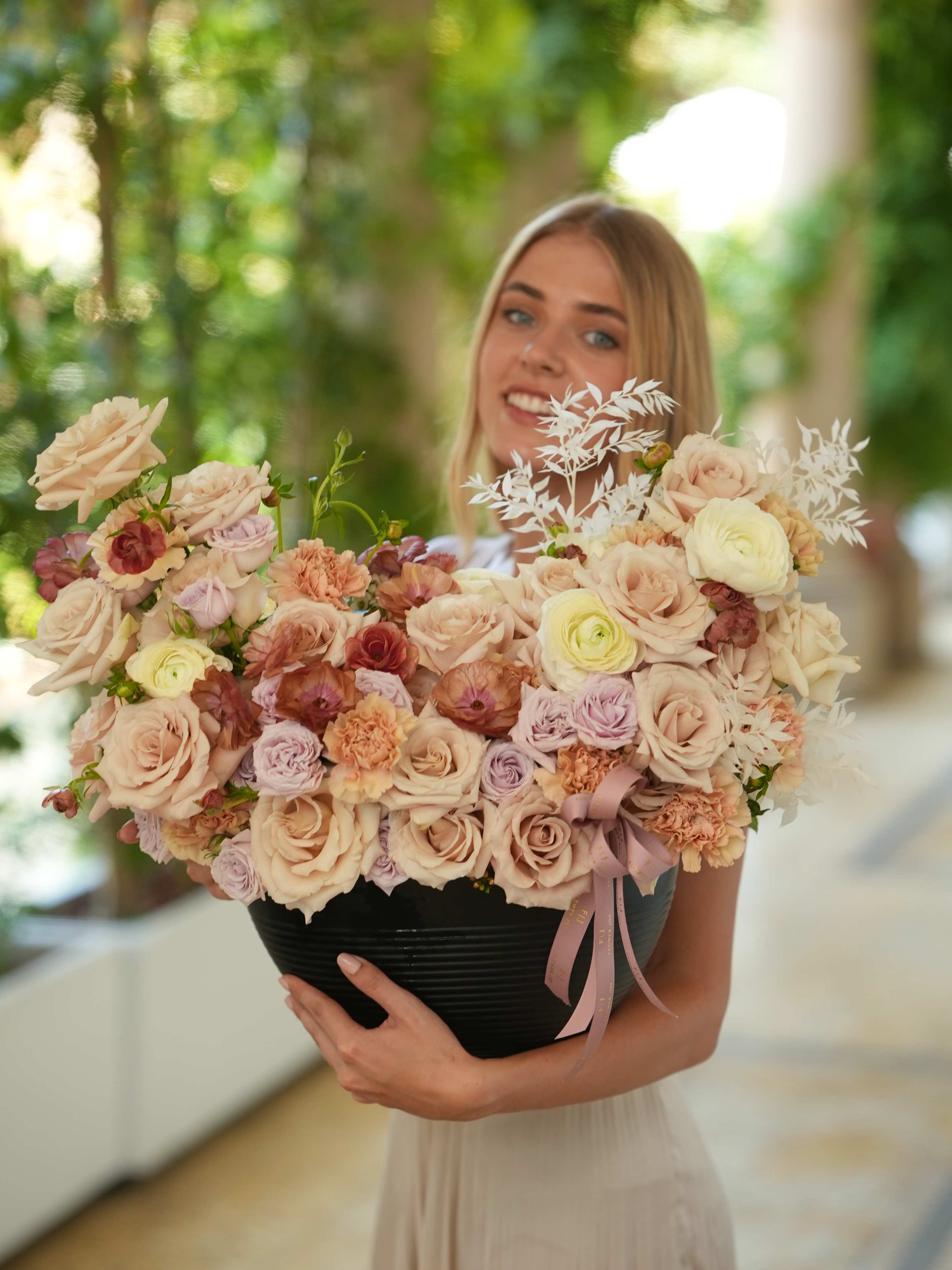 Woman holding a large pastel bouquet in a black container