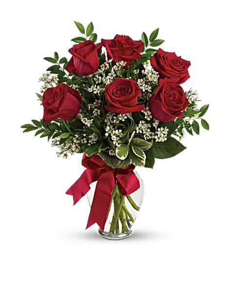 Bouquet of red roses with small white filler flowers in a glass vase