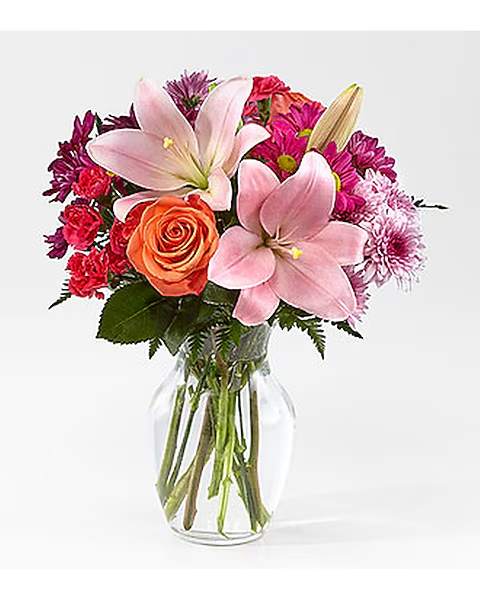 Pink lilies and mixed roses in a clear glass vase
