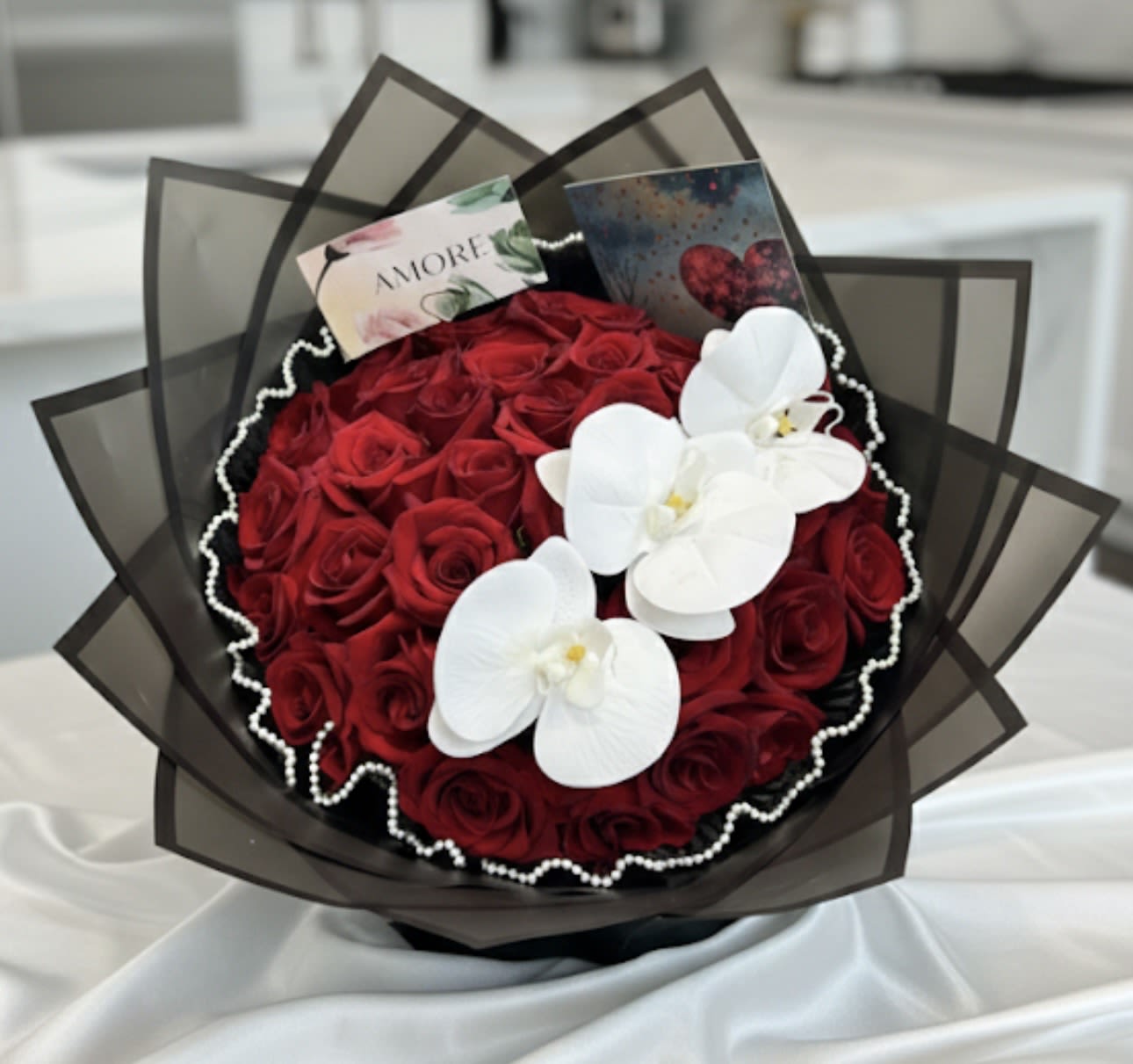Bouquet of red roses with white orchids and dark wrapping