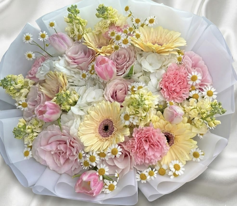 Pastel Garden Luxury Bouquet - The Pastel Garden Luxury Bouquet is a refined floral arrangement designed in a harmonious palette of soft pinks, buttery yellows, and fresh whites. This handcrafted bouquet features premium roses, gerbera daisies, hydrangeas, tulips, carnations, and delicate seasonal accent blooms arranged in a balanced and airy composition.  Inspired by the beauty of a blooming spring garden, this bouquet brings warmth, elegance, and freshness to any occasion. Perfect for birthdays, celebrations, baby showers, or simply sending a thoughtful gesture.  Beautifully wrapped in premium layered presentation for a sophisticated finish.  Each arrangement is handcrafted with fresh seasonal blooms. While flower varieties may vary, the overall style, color story, and premium quality will always be maintained. 