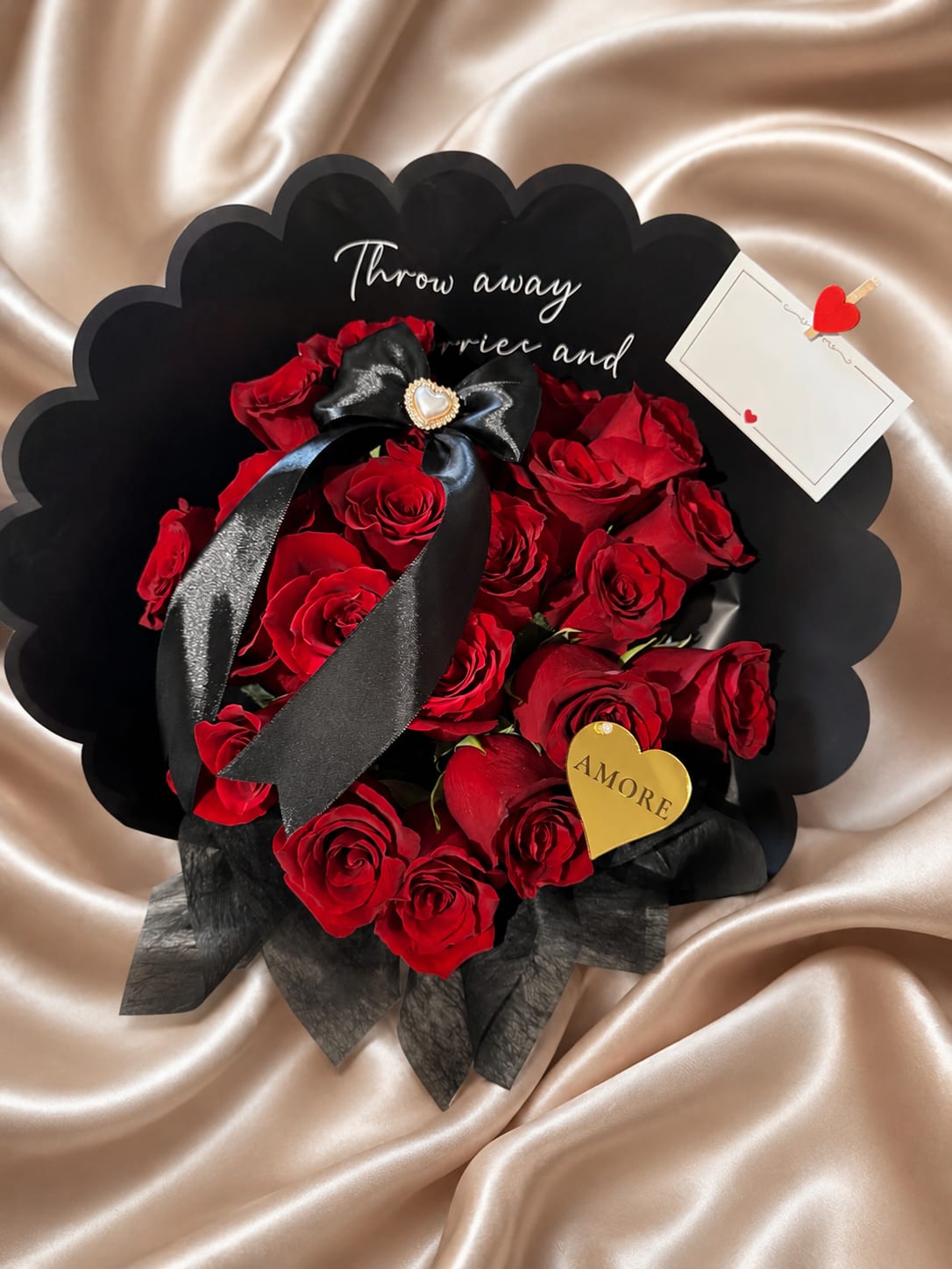 Luxury Red Rose Bouquet – Modern Black Wrap Floral Gift - Make a bold and elegant statement with our Luxury Red Rose Bouquet, a modern floral design crafted for timeless romance.  This premium arrangement features fresh red roses hand-wrapped in sleek black designer-style paper, creating a sophisticated and contemporary presentation. The striking contrast between the deep red roses and the black wrap enhances the luxury feel of this bouquet.  Available in two size options:  • 12 Red Roses – A classic and elegant romantic gesture • 20 Red Roses – A fuller, more luxurious floral expression  Perfect for anniversaries, birthdays, Valentine’s Day, romantic surprises, or any meaningful occasion.  Handcrafted by AMORE in Nashville, Tennessee. Available for local flower delivery in Nashville and surrounding areas. Same-day delivery available based on 