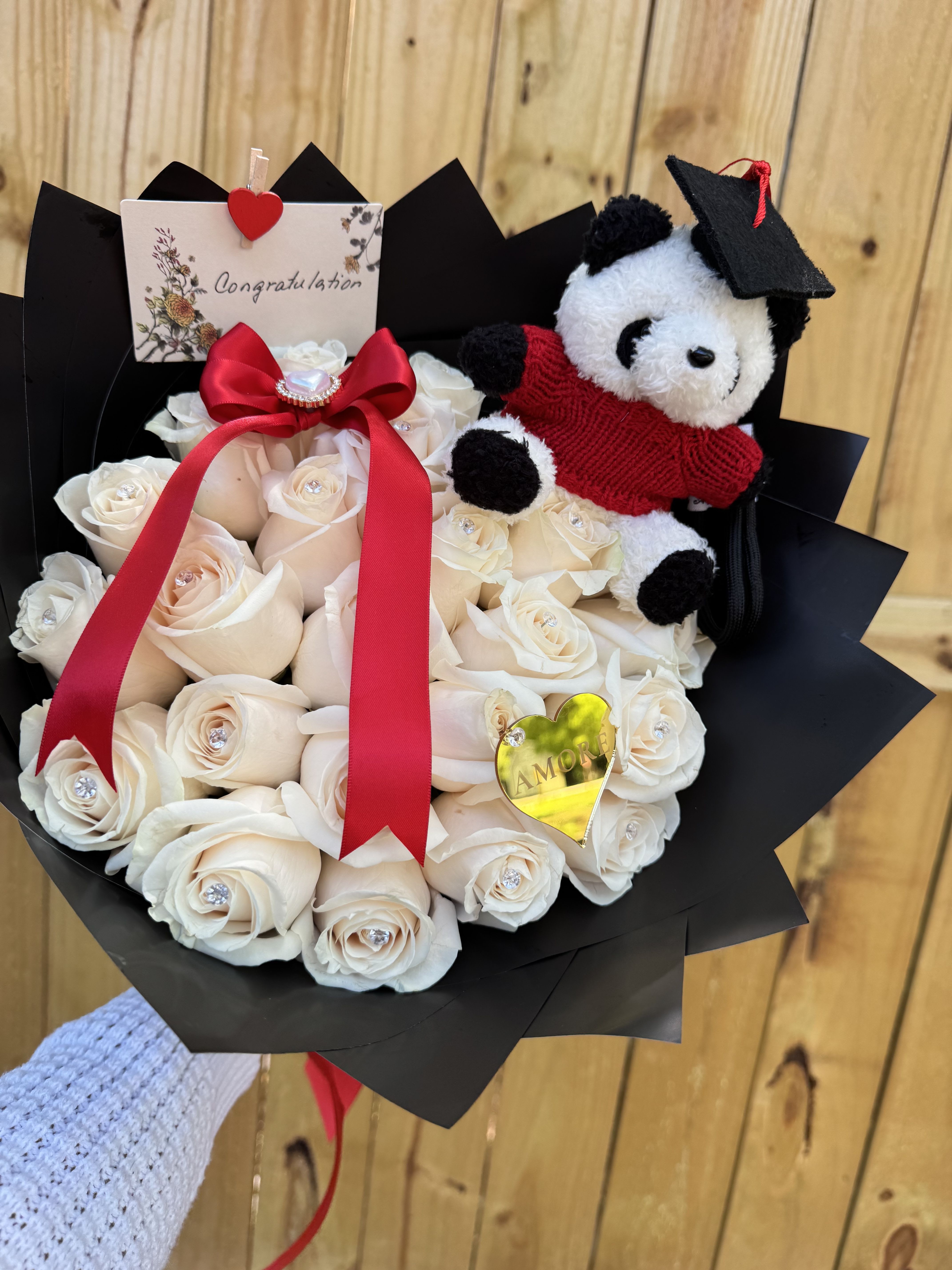 Graduation Rose Bouquet with Plush Bear - A sweet and elegant graduation bouquet designed to celebrate this special achievement. This arrangement includes fresh roses beautifully wrapped and decorated with a graduation plush bear, a congratulation card, and elegant ribbon details.  Available in three sizes: • 25 Roses • 50 Roses • 75 Roses  Rose colors may be selected in red, white, or pink, and the graduation plush bear may come with red or blue outfit depending on availability.  Perfect for graduation ceremonies, school celebrations, college graduates, and meaningful congratulations.