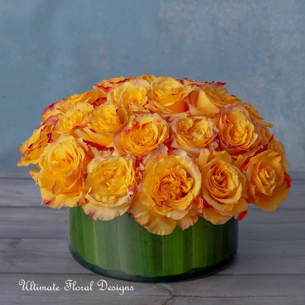 Yellow roses arranged in a low green glass vase