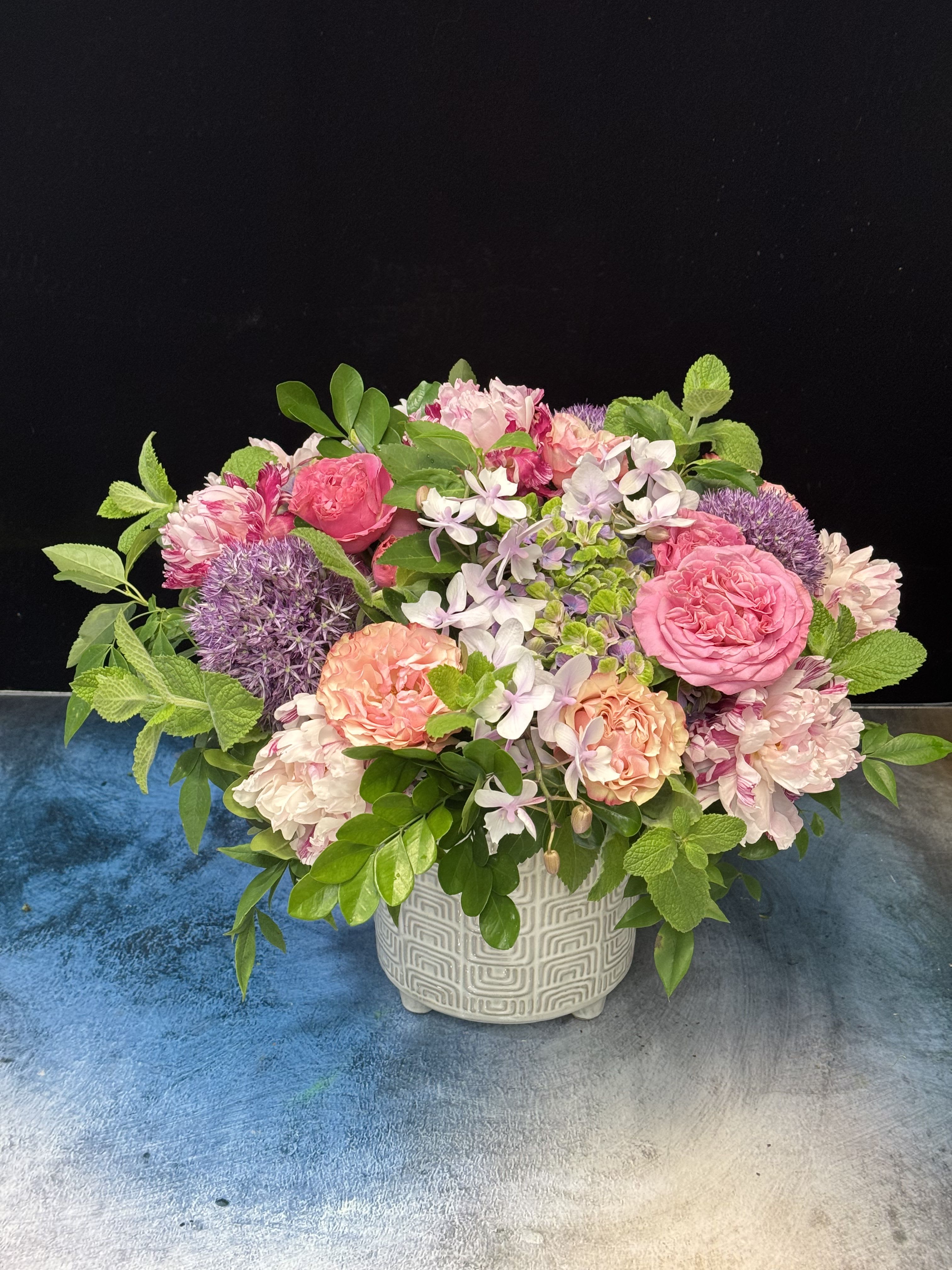 Pink and peach mixed flower arrangement in a patterned ceramic vase