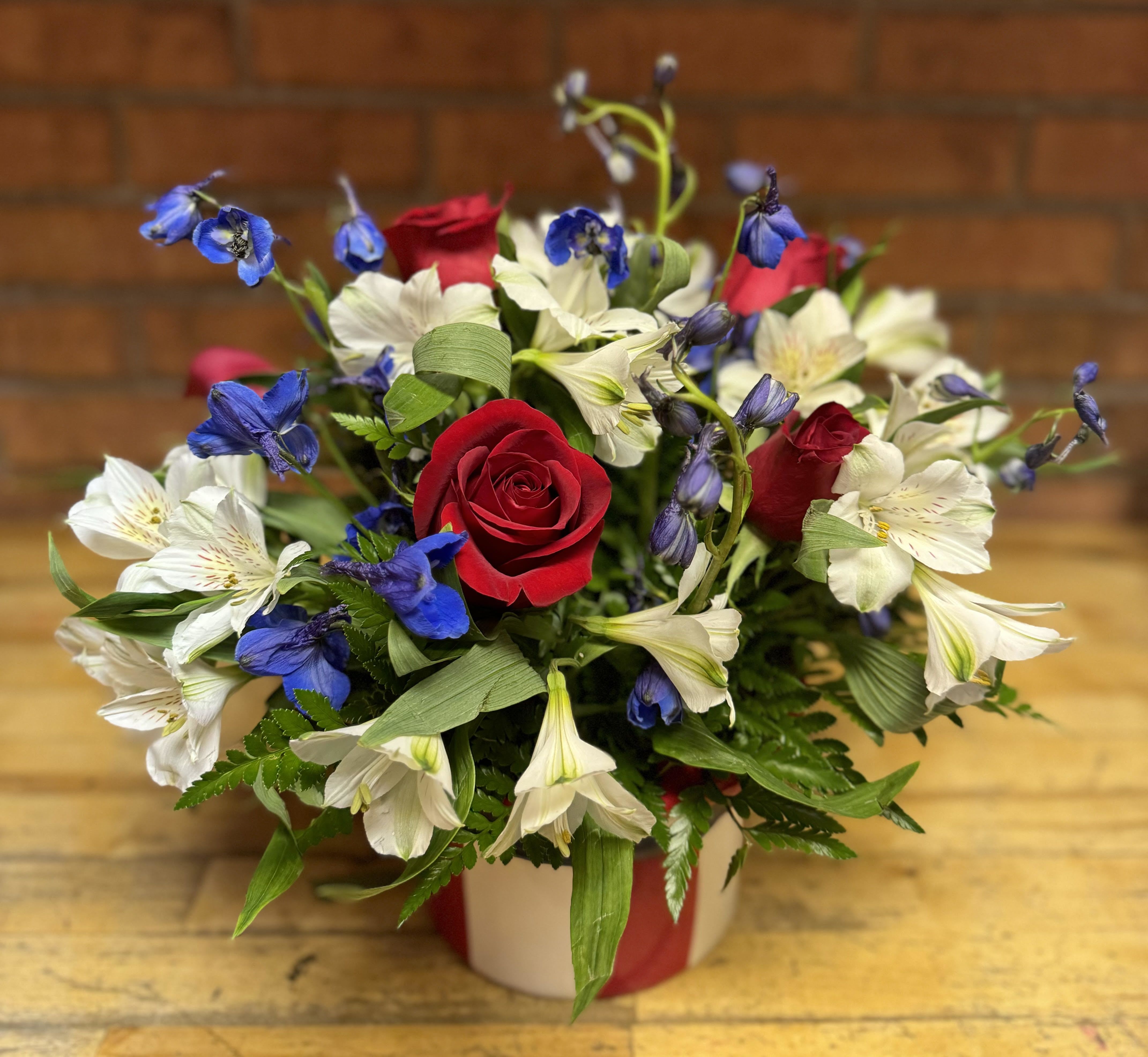 Red roses and white-blue alstroemeria in a wrapped vase arrangement