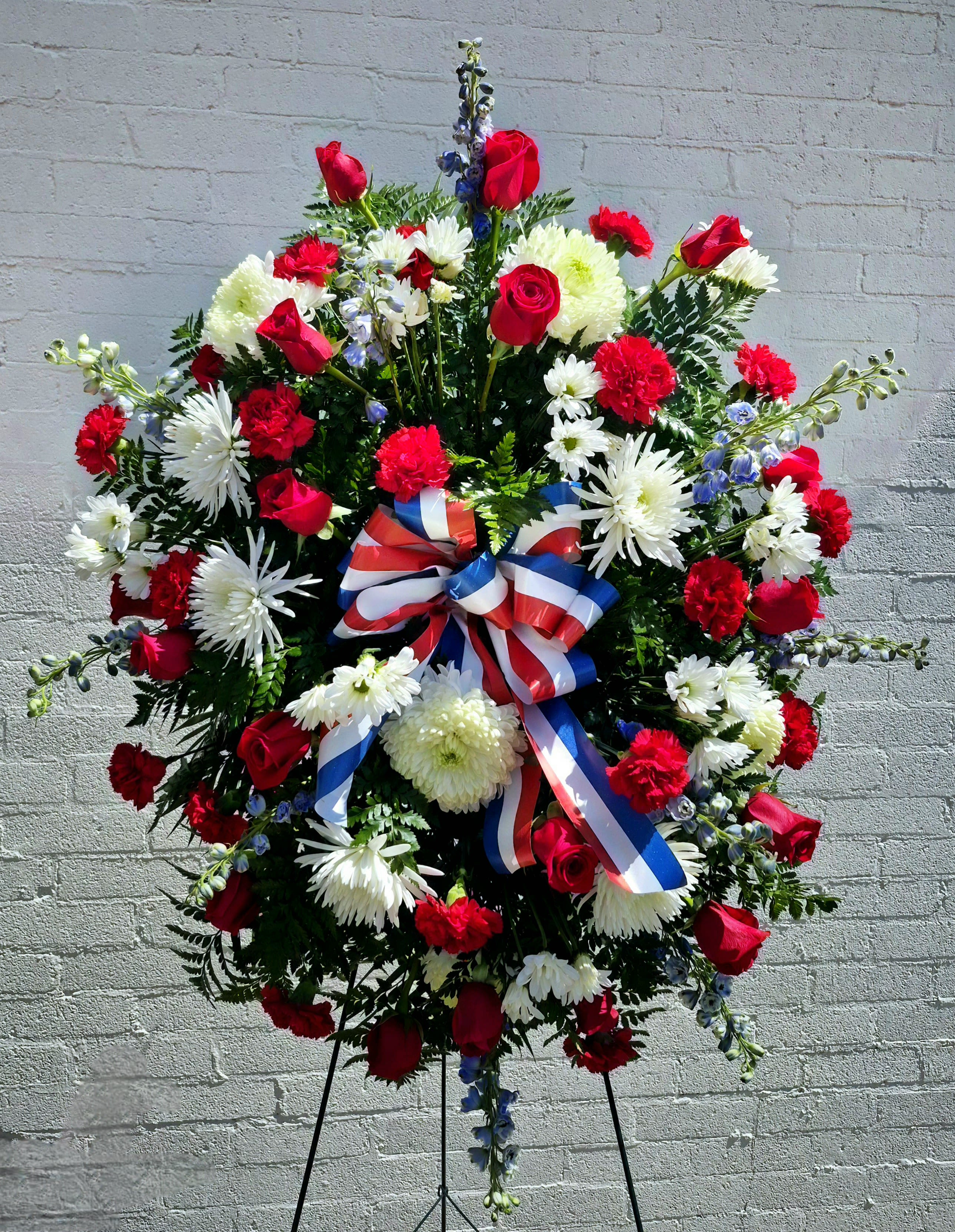 Large red, white, and blue floral standing spray with ribbon bow