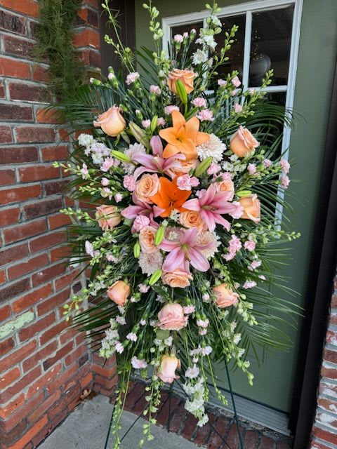 Spirit of Hope Standing Spray - Share the spirit of hope and faith with a generous standing spray of pink and orange blossoms – including lilies, roses and carnations – against a backdrop of fresh palm fronds. A lovely way to express your sympathies.