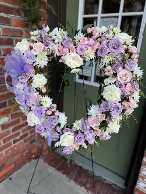 Heart-shaped floral wreath with lavender, pink, and white flowers on an easel