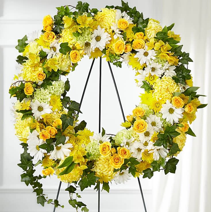 Golden Remembrance Wreath - Whether yellow was their favorite color or it captures the essence of their radiance, a ring of bright blooms thoughtfully displays your sentiment. Our Golden Remembrance Wreath is composed of spray roses, daisy pompons, carnations and more. Each flower is selected to beautifully accent one another and the love you are sending. 