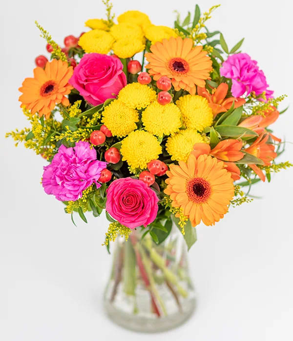 Tropical Sunset bouquet - This hand tied arrangement is bursting with vibrant blooms, including yellow, cerise, purple, and orange stems, decorated with seasonal foliage.