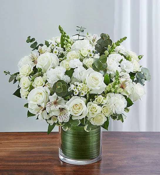 Cherished Memories All White - Memories are timeless treasures of the heart, meant to be cherished. Our striking, all-white sympathy arrangement of roses, snapdragons, alstroemeria and more, elegantly designed by hand in a graceful cylinder vase, is a touching tribute to a life well lived and the memories that will be held dear forever.