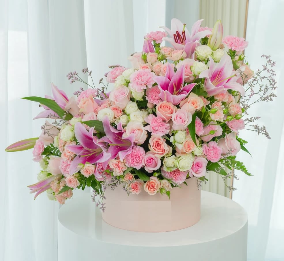 Pink and white floral arrangement in a round box