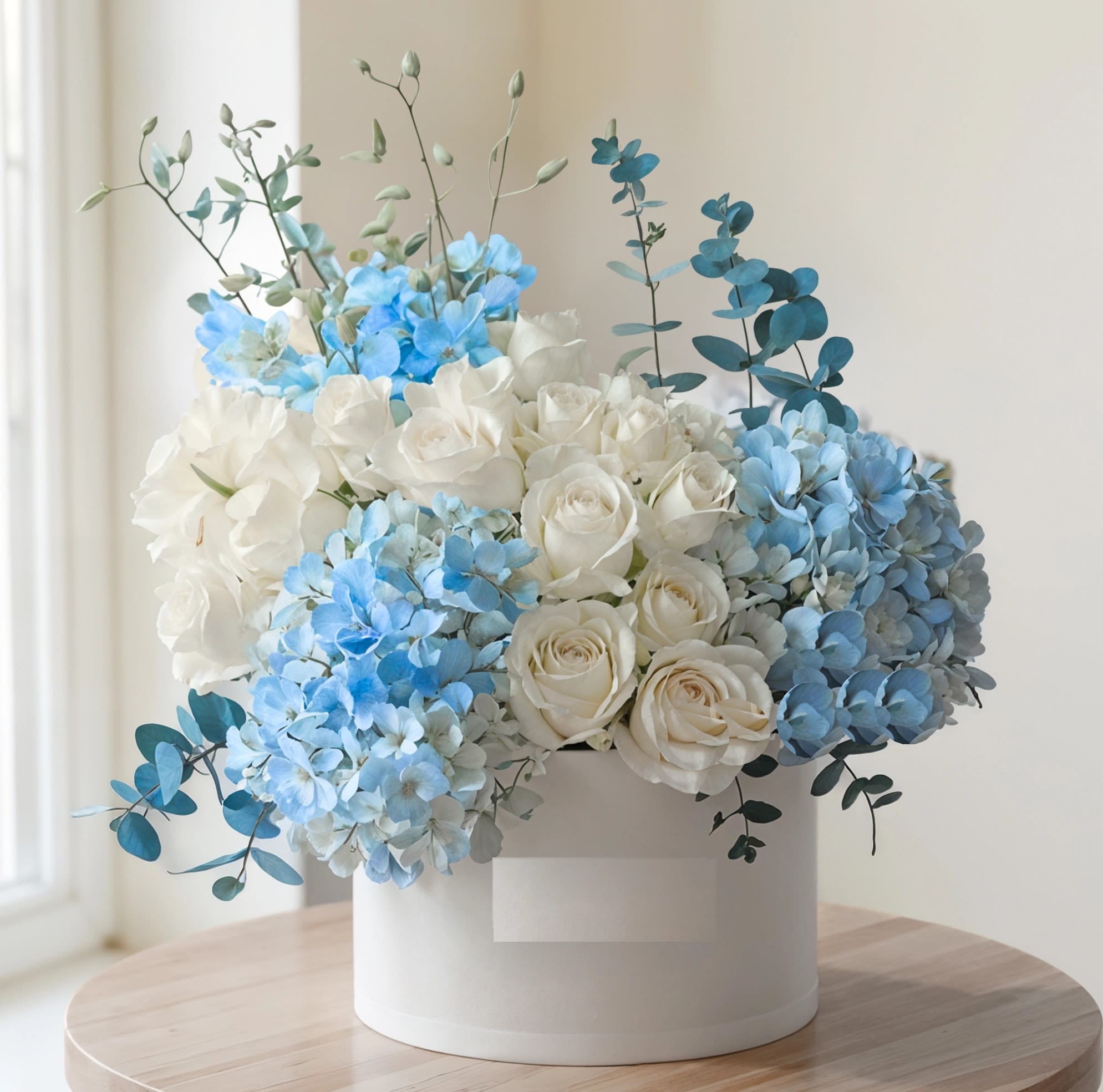 White roses and blue hydrangeas arranged in a white box