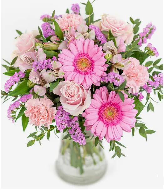 Pink gerbera daisies and roses in a glass vase