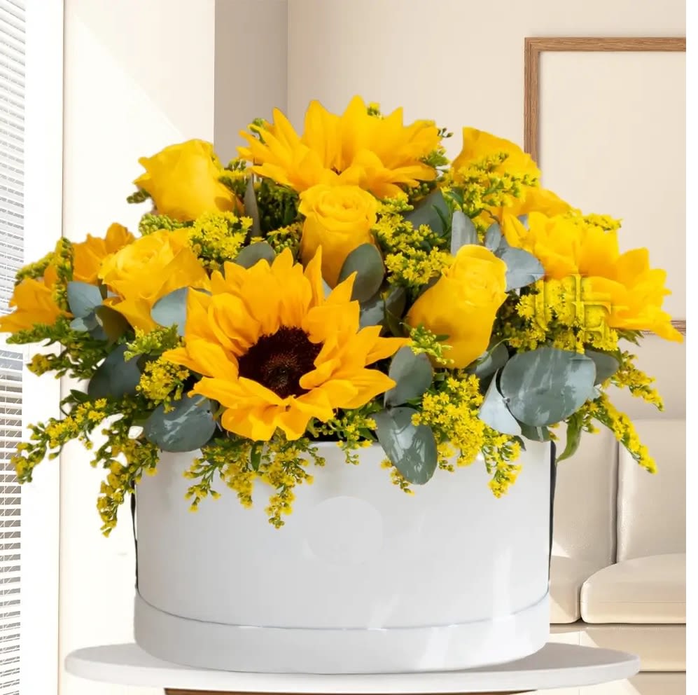 Yellow roses and sunflowers arranged in a white hat box