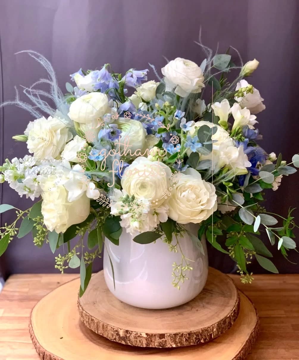 White and pale blue floral arrangement in a white vase