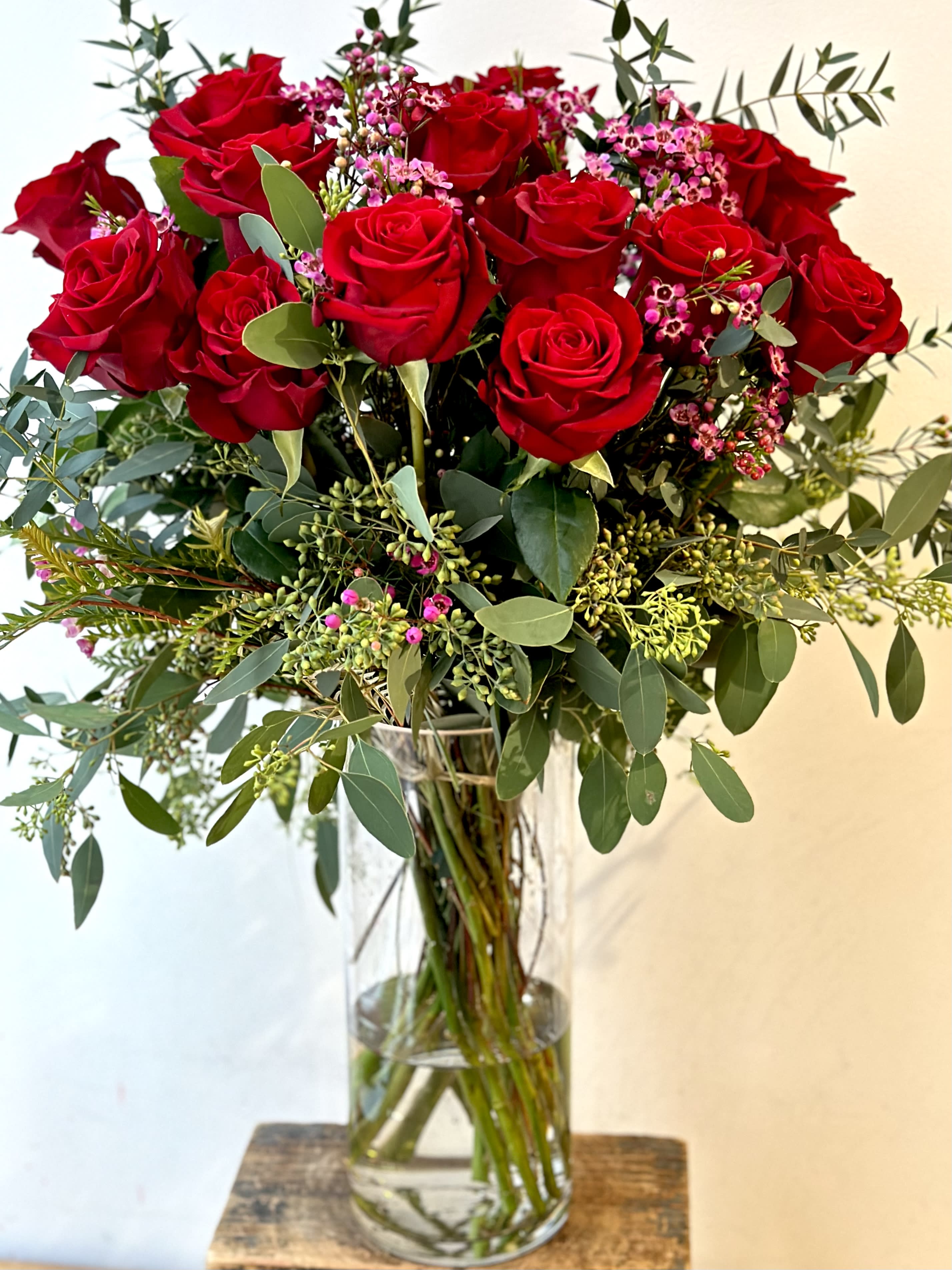 Bouquet of red roses with pink filler flowers in a clear glass vase