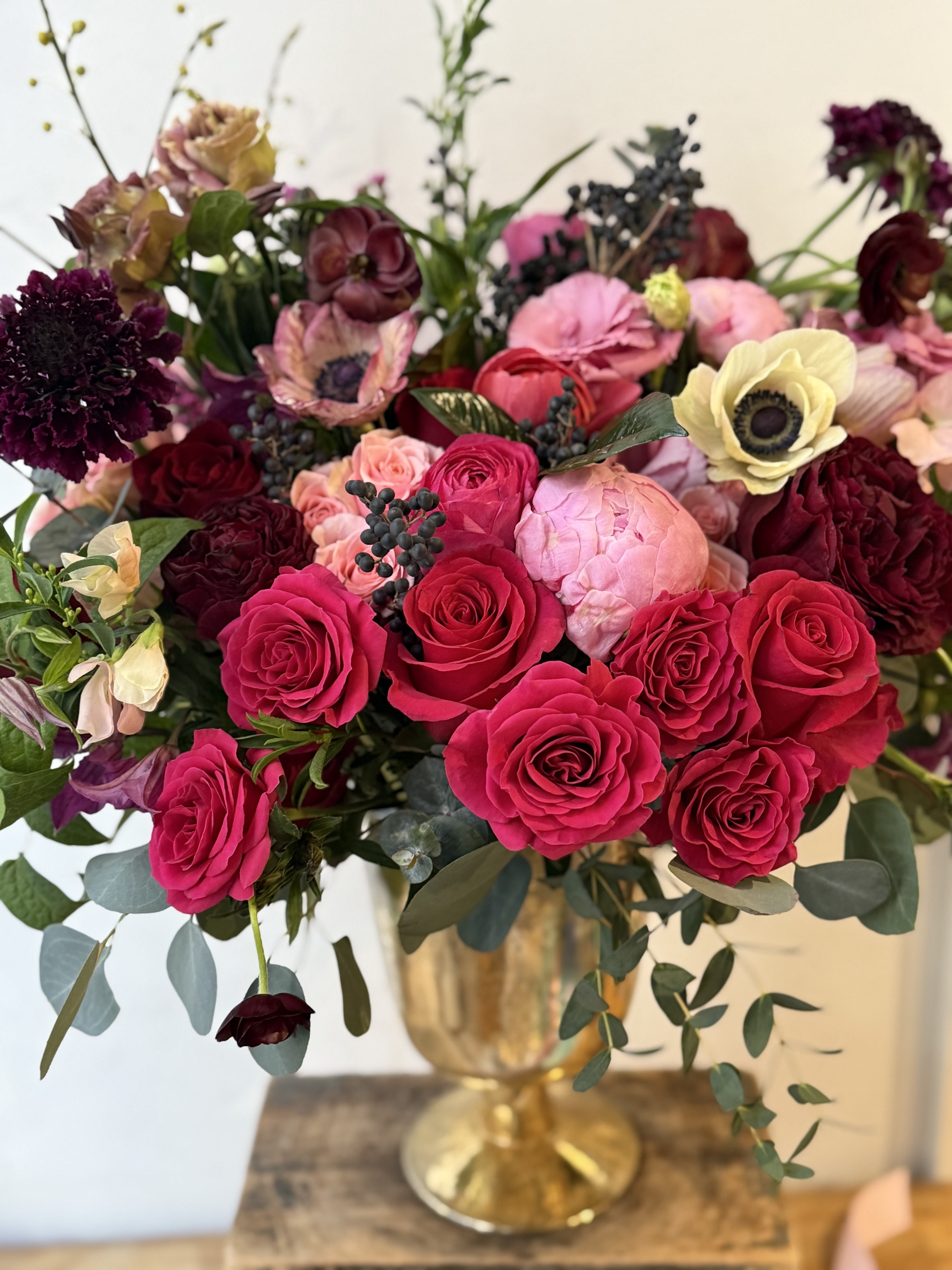 Bouquet of hot pink and burgundy roses in a gold vase