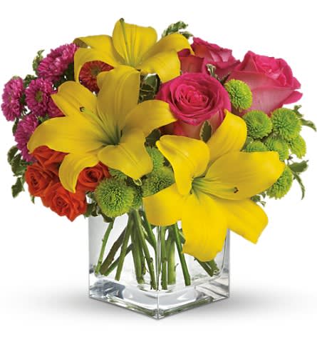 Bouquet of yellow lilies, pink roses, and purple mums in a clear square vase