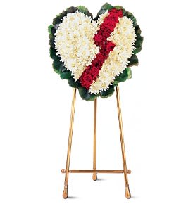 Heart-shaped funeral wreath of white and red flowers on a stand