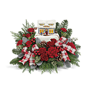 Christmas floral arrangement with red roses and plaid ribbons around a house ornament