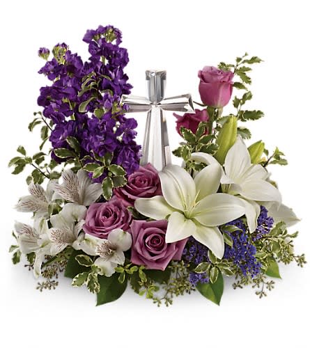 Purple and white floral arrangement with a silver cross centerpiece