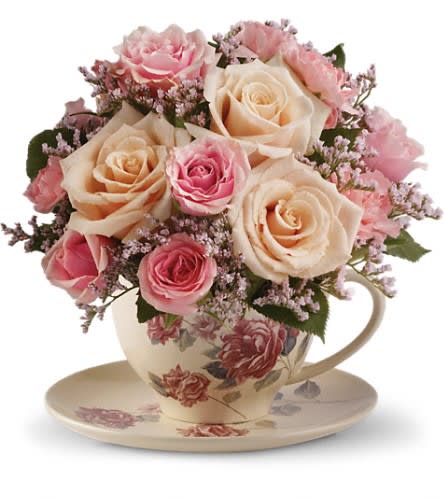 Pink and cream roses arranged in a teacup with matching saucer