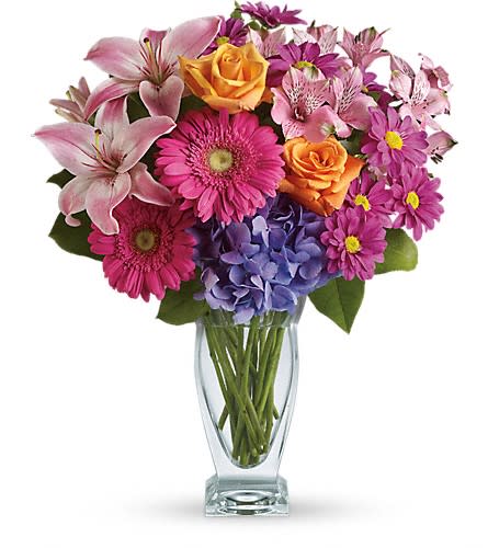 Mixed bouquet of pink, purple, and orange flowers in a clear glass vase
