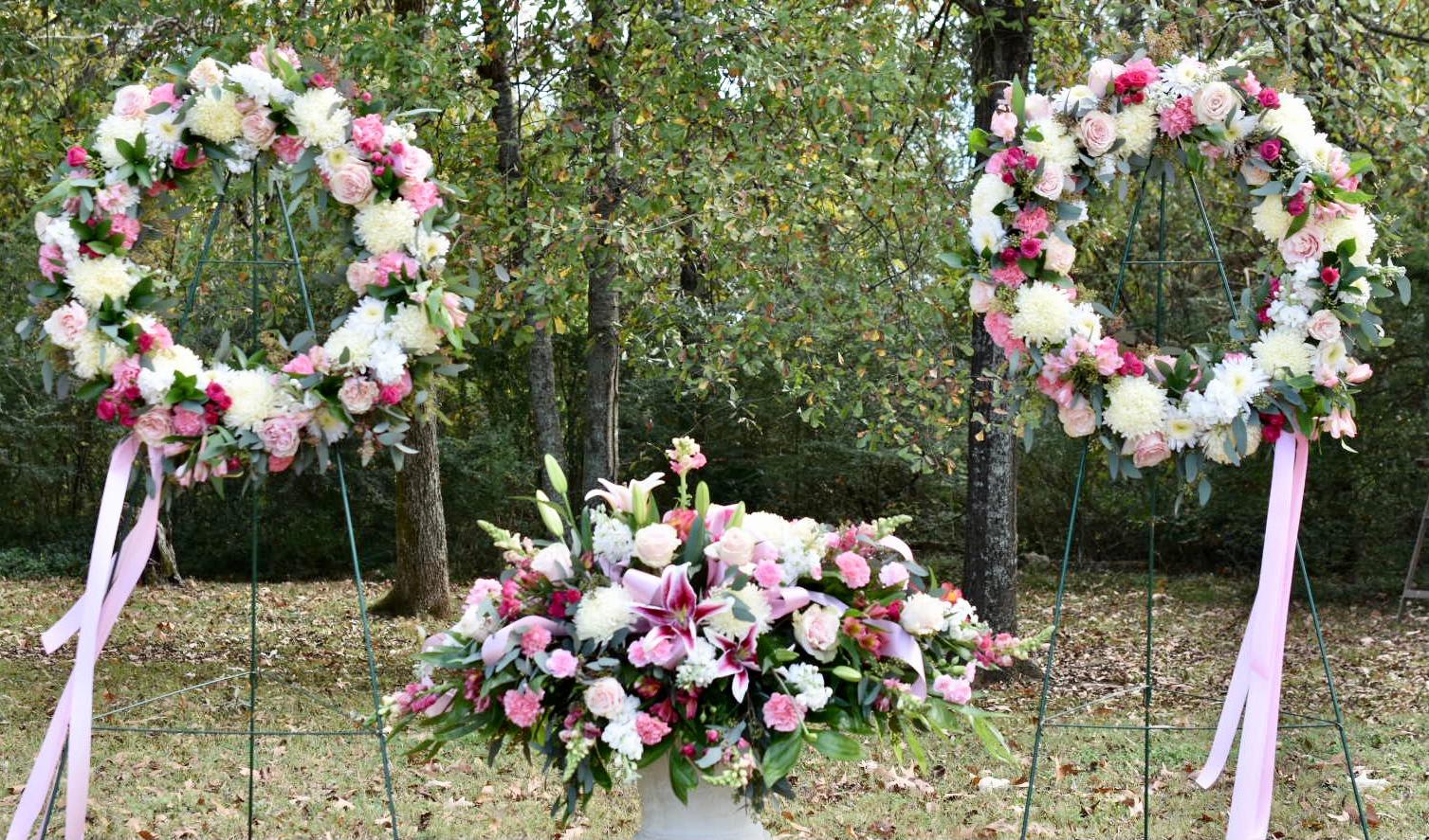 Three pink and white floral wreaths and a matching centerpiece outdoors