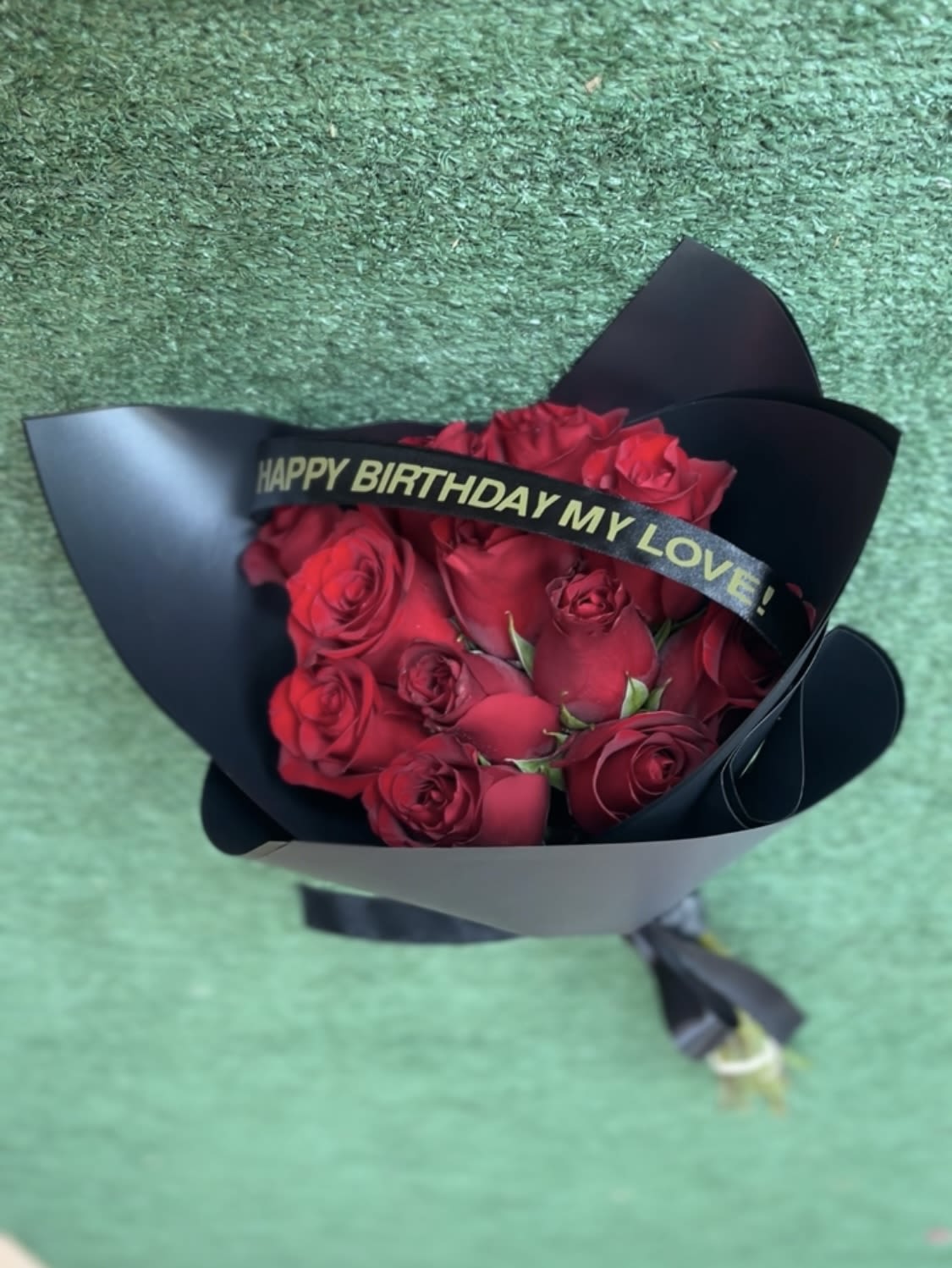 Bouquet of red roses wrapped in black paper with a birthday ribbon