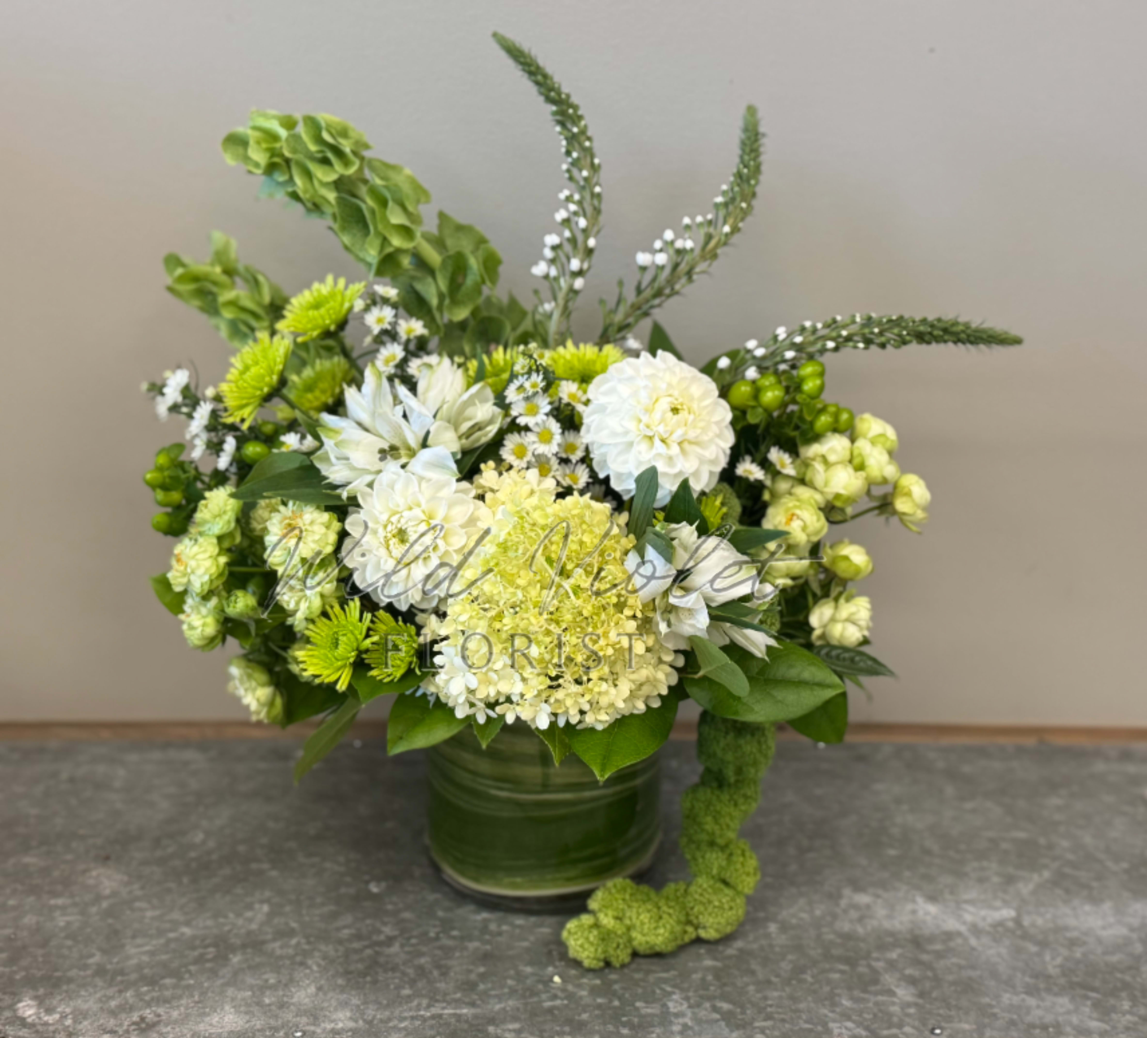 Green and white floral arrangement in a glass vase