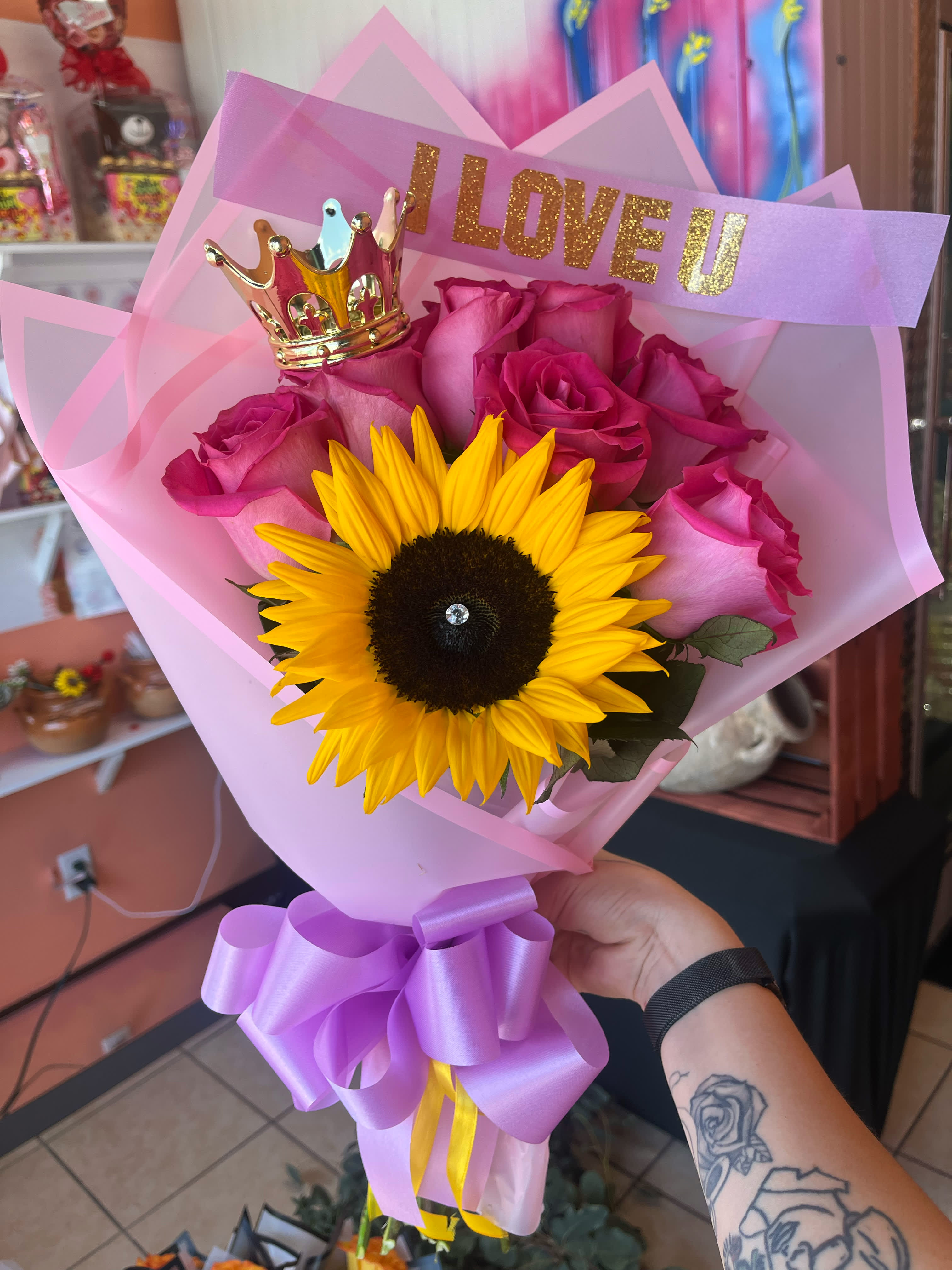 Pink rose bouquet with a sunflower, crown topper, and "I LOVE U" sign